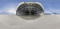 the view from inside a building through a fish eye lens, looking straight at a hangar