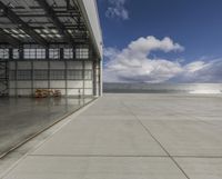 a plane is parked inside a large hangar at the airport in daylight, with a lot of glass on the outside