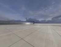 a jet airplane is on an empty runway in front of a gray sky with dark clouds