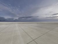 airplane parking on runway at desert with mountains in distance under cloudy sky while clouds are blue