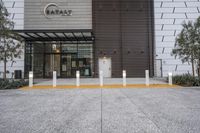 a building has a metal and wood exterior, and a concrete curb in front has some yellow columns