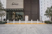 a building has a metal and wood exterior, and a concrete curb in front has some yellow columns