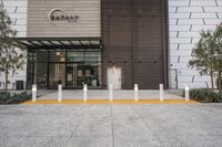 a building has a metal and wood exterior, and a concrete curb in front has some yellow columns