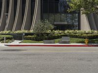 the yellow fire hydrant is near the large modern building on the side of the road