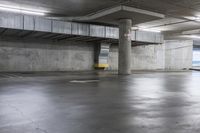 an empty parking garage with large cement columns, and concrete flooring and painted walls