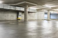 an empty parking garage with large cement columns, and concrete flooring and painted walls