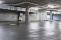 an empty parking garage with large cement columns, and concrete flooring and painted walls