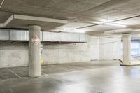 an empty parking garage with large cement columns, and concrete flooring and painted walls