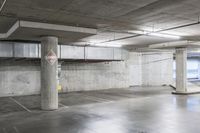 an empty parking garage with large cement columns, and concrete flooring and painted walls