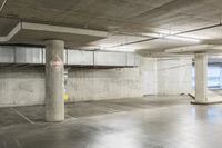 an empty parking garage with large cement columns, and concrete flooring and painted walls