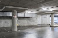 an empty parking garage with large cement columns, and concrete flooring and painted walls