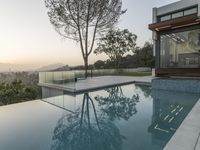 large swimming pool with glass fenced in area of home overlooking mountain range at dusk