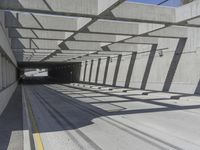 a large long narrow tunnel with one side facing towards the camera, which is paralleled by two concrete pillars