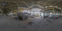 fisheye image of the inside of a building with people standing outside it and looking at machinery