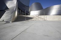 a large gray building with white concrete walls and metal stairs in front of it on a blue sky