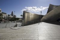 a large gray building with white concrete walls and metal stairs in front of it on a blue sky