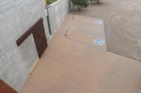 a parking spot with painted lines is near a building by the river bank near an olive tree