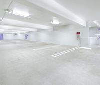 empty parking lot with two large white signs on the wall and several lights above it