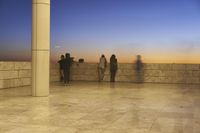 the wall has columns near a railing overlooking the water, and a light beam has been cast