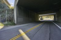 the view from inside an underpass showing the road and tunnel and trees in the distance