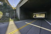 the view from inside an underpass showing the road and tunnel and trees in the distance