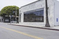 an empty street in front of buildings with windows on each side and two traffic cones on the other side