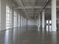 an empty industrial warehouse with cement floors and ceilinging in the middle of it is looking into a building