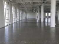 an empty industrial warehouse with cement floors and ceilinging in the middle of it is looking into a building