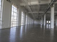 an empty industrial warehouse with cement floors and ceilinging in the middle of it is looking into a building