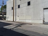 two white commercial buildings on an empty street corner with blue skies above them and one red fire hydrant next to it