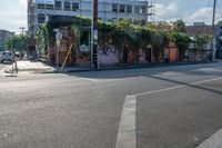 the empty street is busy with cars and shops in the background, the man with a skateboard is crossing the intersection