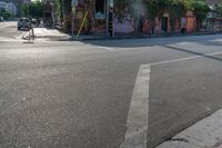 the empty street is busy with cars and shops in the background, the man with a skateboard is crossing the intersection