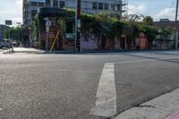 the empty street is busy with cars and shops in the background, the man with a skateboard is crossing the intersection