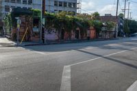 the empty street is busy with cars and shops in the background, the man with a skateboard is crossing the intersection