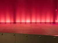 the interior of an auditorium with red lights and a glass wall as backdrop for a show