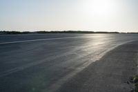 an empty road near a beach and waves as well as cars on the sand and houses on the beach