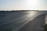 an empty road near a beach and waves as well as cars on the sand and houses on the beach