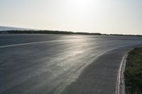 an empty road near a beach and waves as well as cars on the sand and houses on the beach