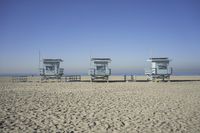 people walk on sand at a beach, near the ocean in the distance is a sky with few cloudless, and blue skies