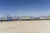 people walk on sand at a beach, near the ocean in the distance is a sky with few cloudless, and blue skies