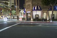 an intersection with stop lights, city street signs and many buildings are lit up at night