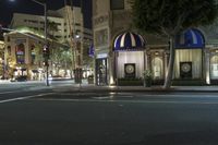 an intersection with stop lights, city street signs and many buildings are lit up at night