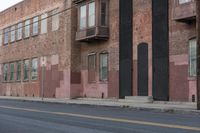 a red and brown building is on the side of the street as the man rides a skateboard