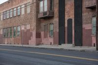 a red and brown building is on the side of the street as the man rides a skateboard