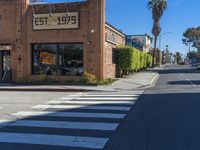 a crosswalk on a busy street with buildings along the side of it and people walking in the background