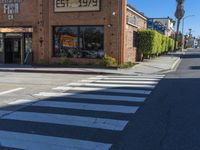 a crosswalk on a busy street with buildings along the side of it and people walking in the background