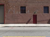 the brick building has an open red door on it's side and an umbrella on the pole at the top