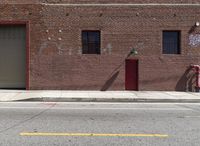 the brick building has an open red door on it's side and an umbrella on the pole at the top