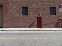 the brick building has an open red door on it's side and an umbrella on the pole at the top