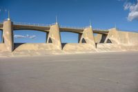 a large concrete structure with a long sidewalk underneath it, as if in an airplane port